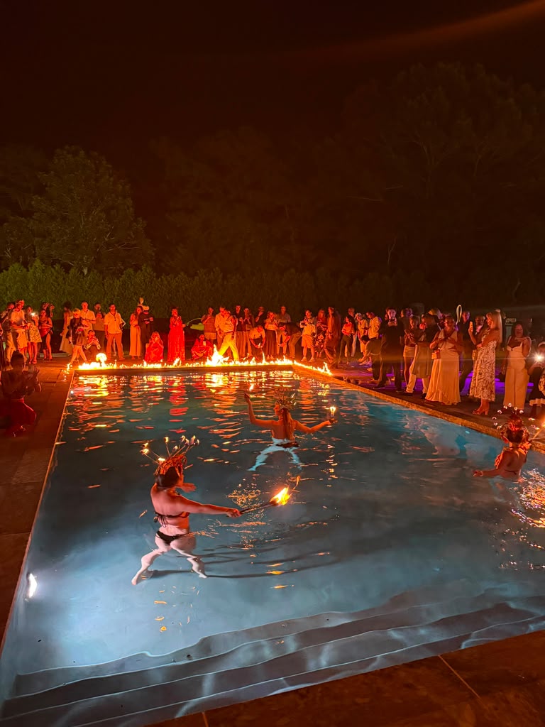 Fire dancers perform in the pool as guests watch from the water's edge at The Art Affair