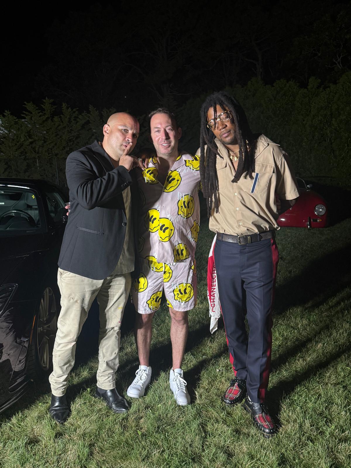 Eddy Bogaert and friends posing beside vintage sports cars at night during The Art Affair weekend