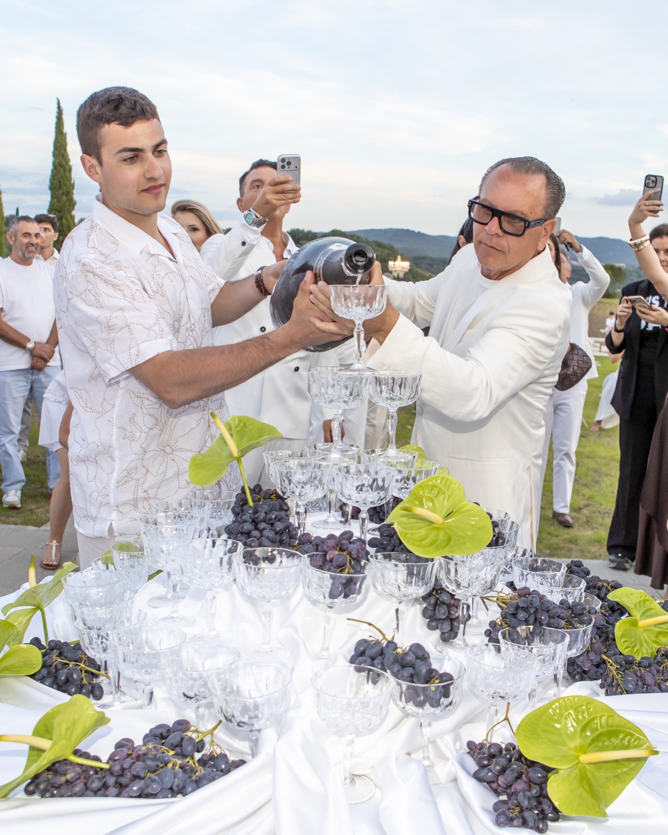 Champagne being poured over a tower of coupe glasses