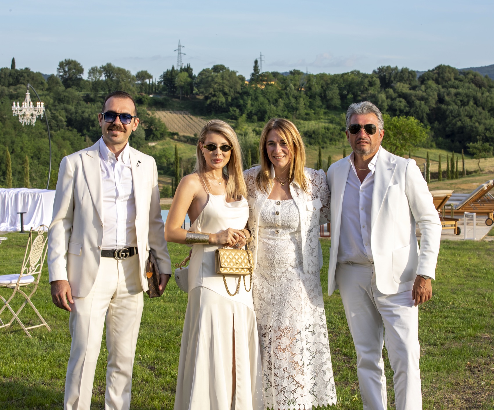 Guests dressed in white with the Tuscan countryside behind them