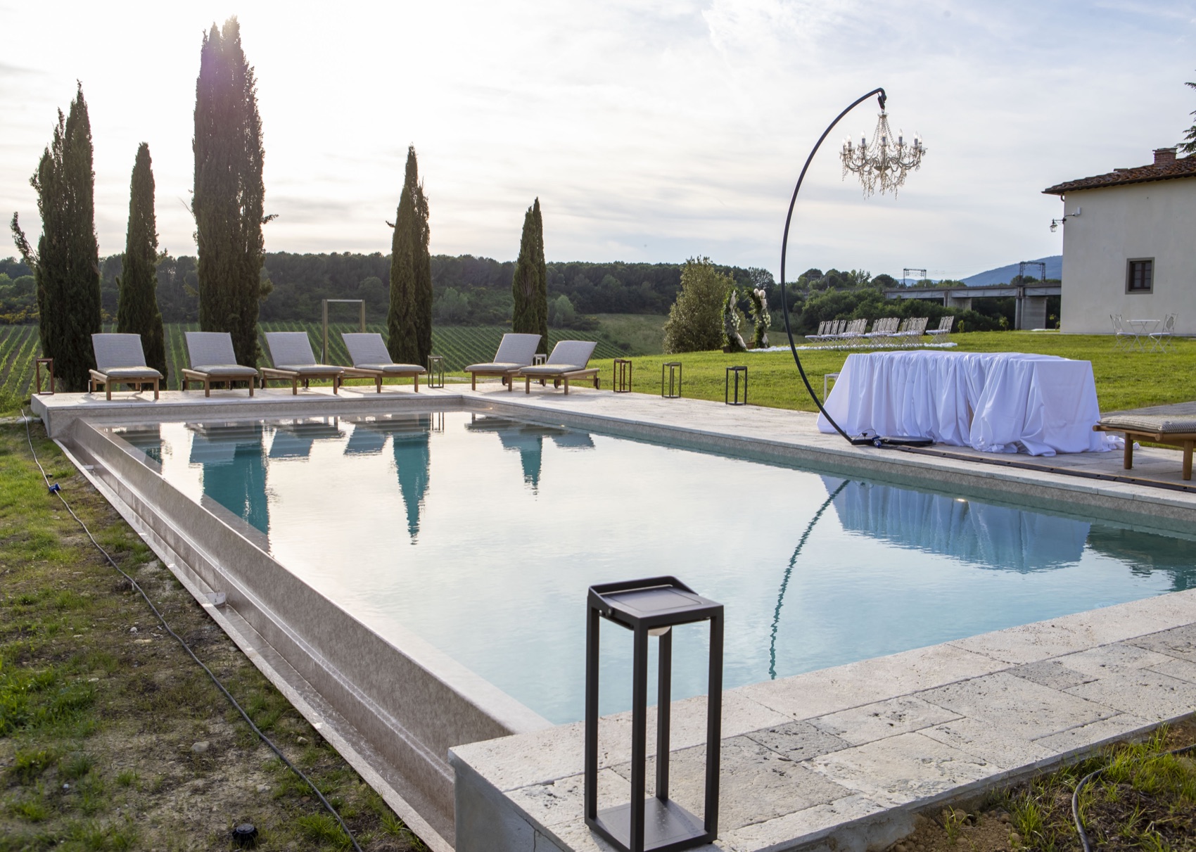 The villa pool with a chandelier and cypress trees at golden hour